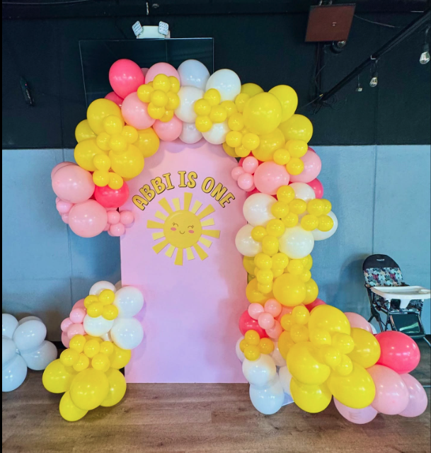 Baby is One first birthday balloon arch with yellow and pink balloons